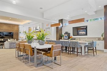 A dining area with a table and chairs and a kitchen with a television